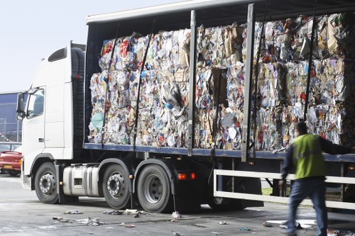Worker wearing PPE loading a skip with safety measures in place